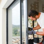 handsome-young-man-installing-bay-window-in-a-new-house-construction-picture-id945455370